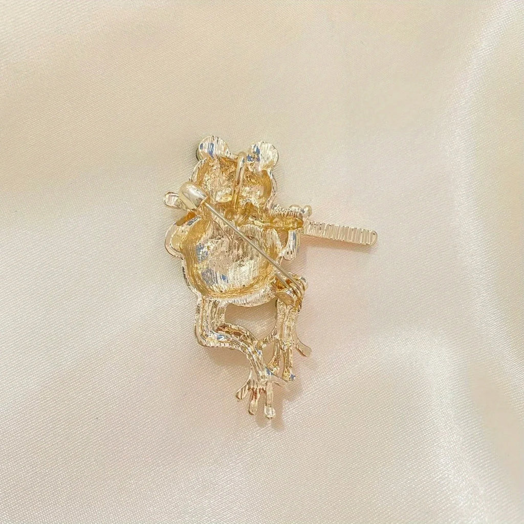 The Piping Frog Brooch on a cream background