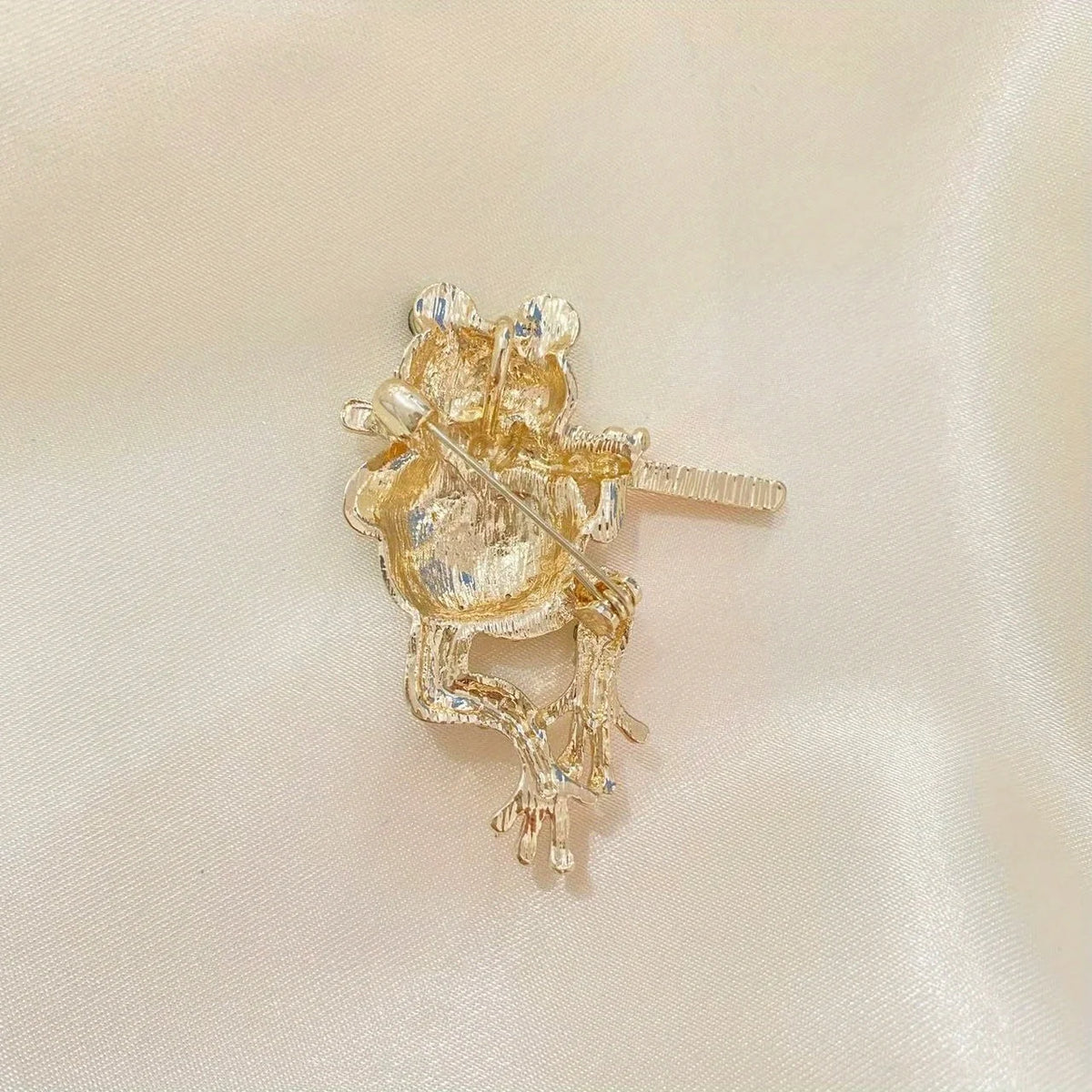 The Piping Frog Brooch on a cream background
